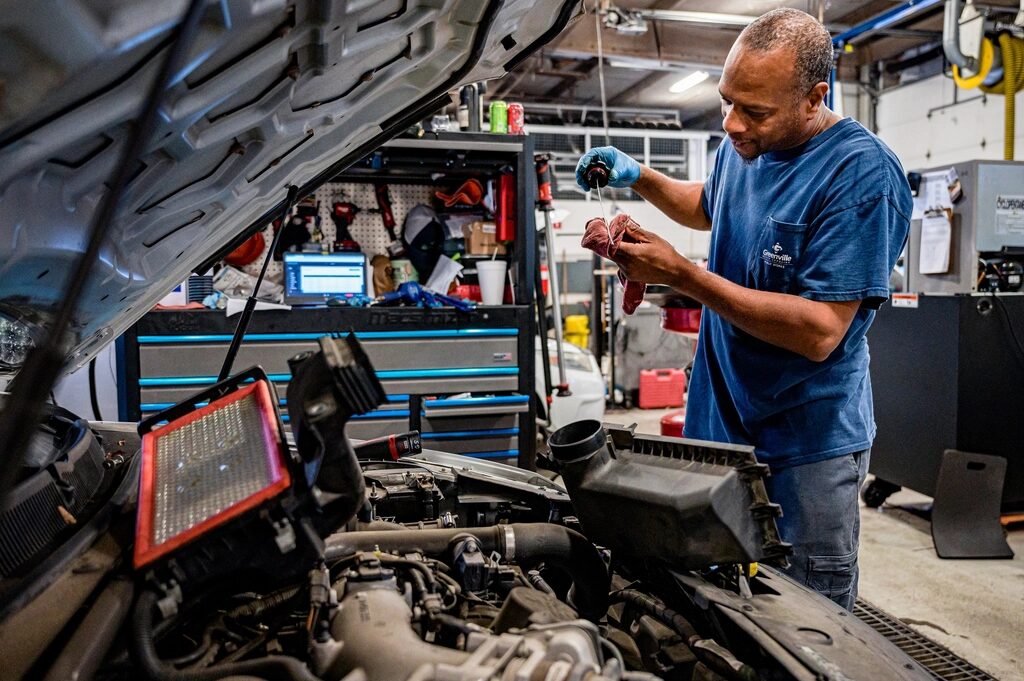 Mechanic checking the oil under an open hood
