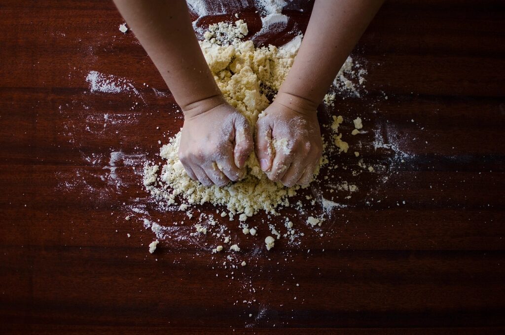 Hands mixing dough on a floured table