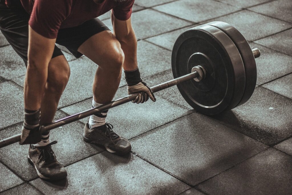 Person lifting a barbell from the gym floor