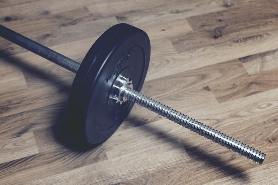 Barbell resting on a wood gym floor
