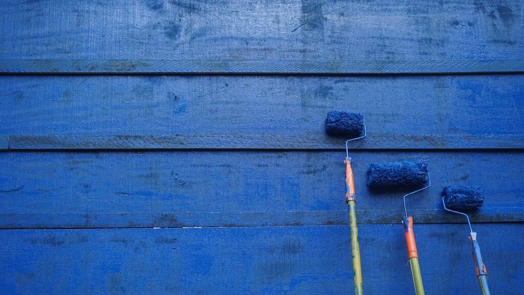 Three rollers resting against blue painted boards