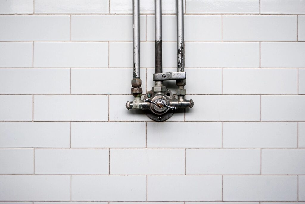 Exposed water pipes and valve against a tiled wall