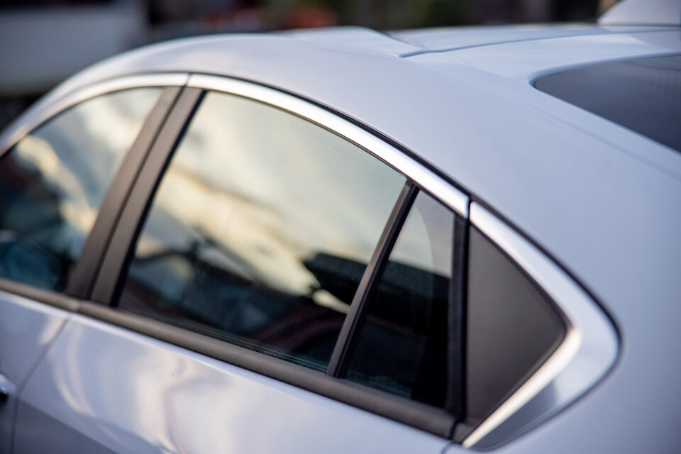Side windows of a silver car reflecting the sky